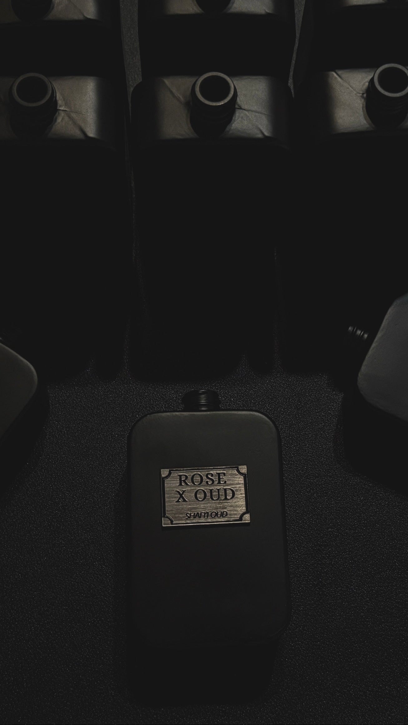 Black perfume bottle labeled 'Rose x Oud' on a dark background